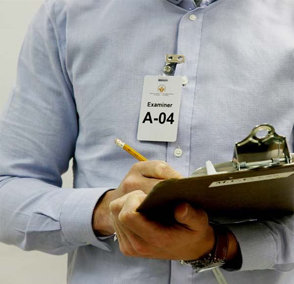 Decorative cropped image of an examiner writing on a clipboard